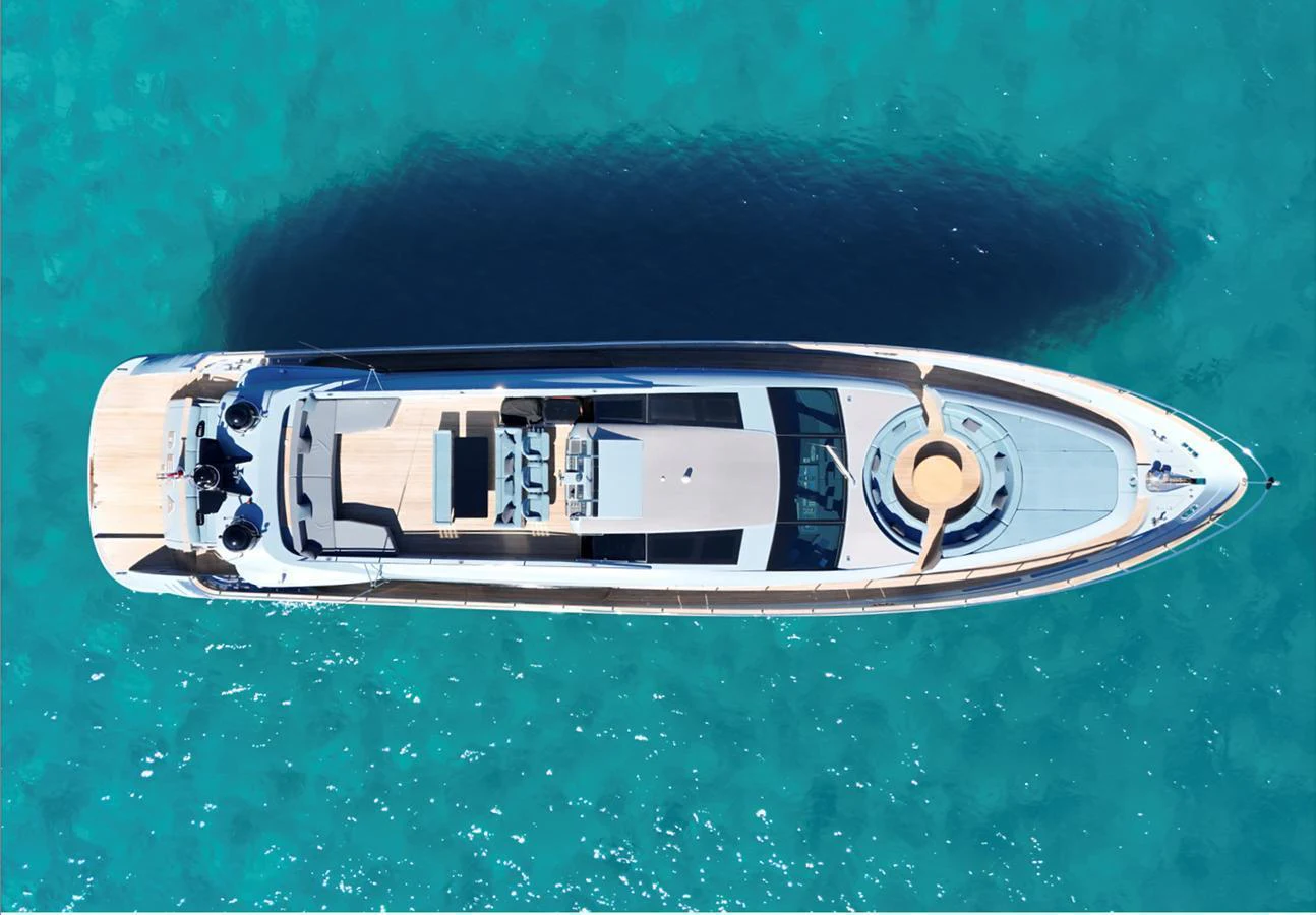 An elegant yacht glides through crystal-clear waters, showcasing its sleek design from an aerial perspective. aboard DEEA II Yacht for Sale