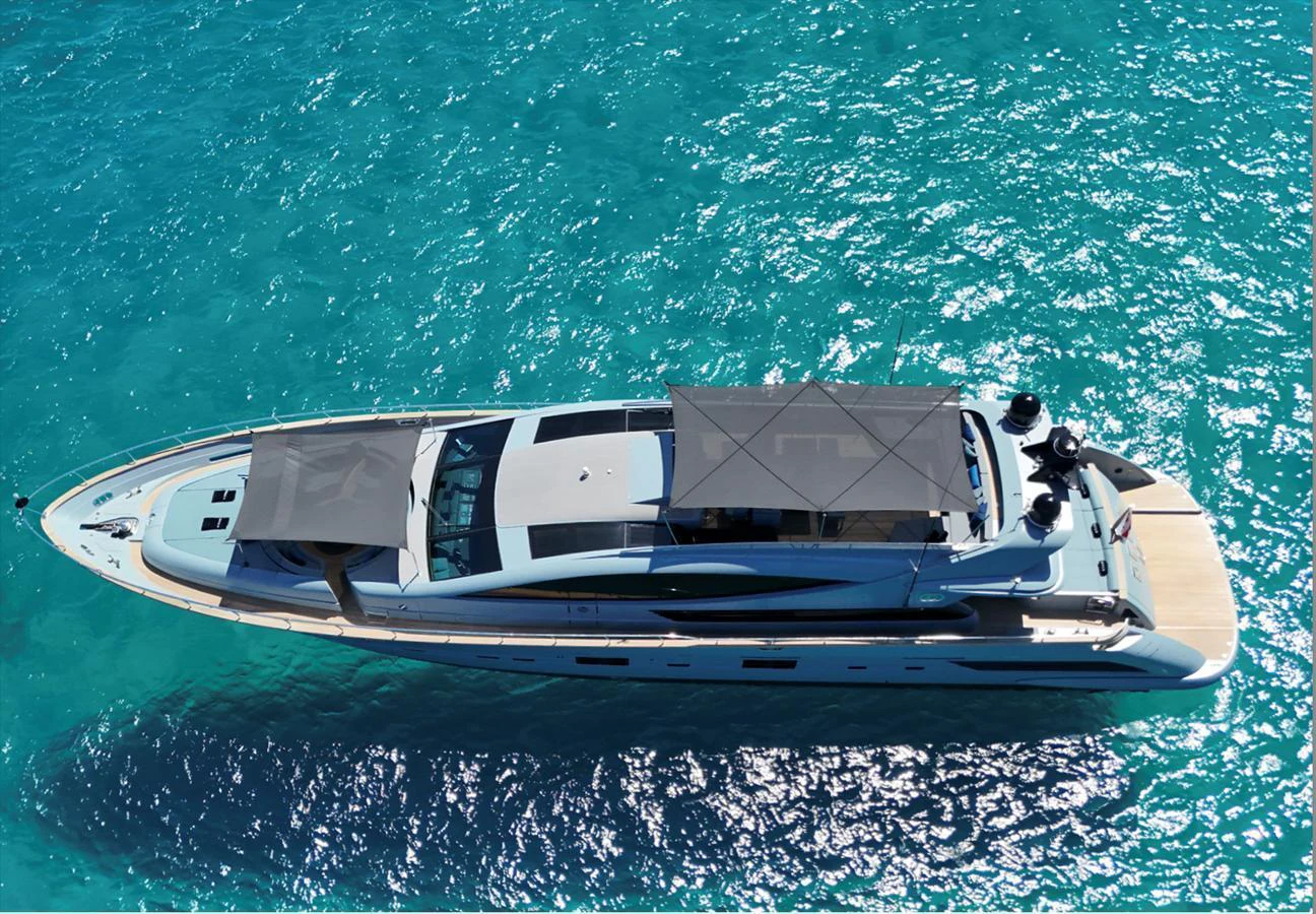 An elegant yacht glides through crystal-clear turquoise waters, showcasing its sleek design from an aerial perspective. aboard DEEA II Yacht for Sale