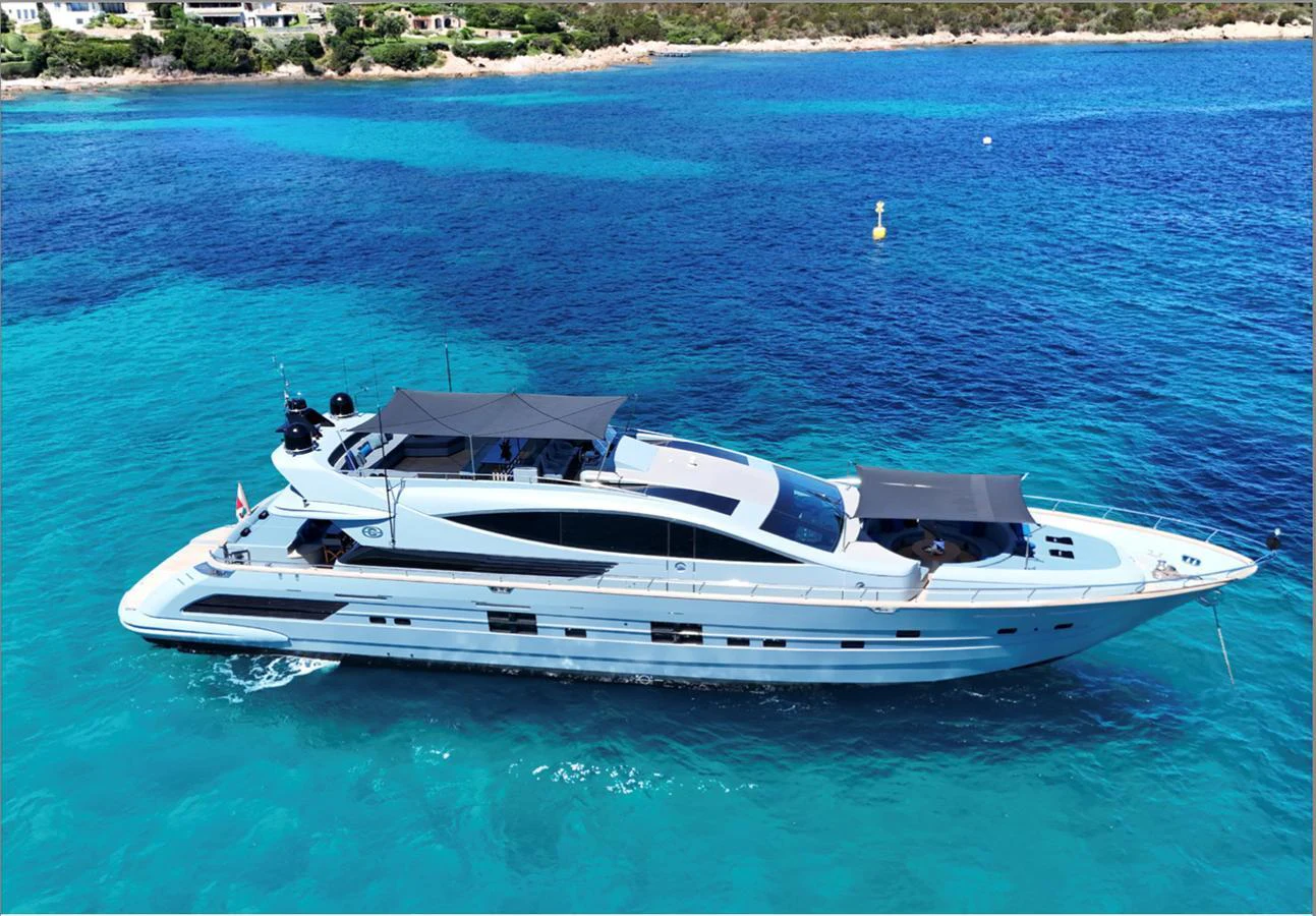 A sleek and modern yacht glides gracefully on crystal-clear blue waters near a scenic coastline. aboard DEEA II Yacht for Sale