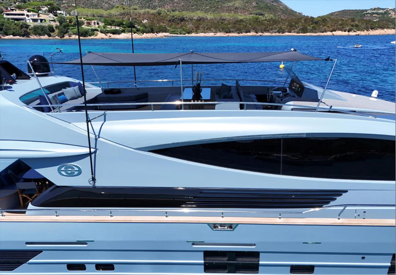 A sleek yacht with a modern design is anchored in a serene coastal area, showcasing its elegant lines and spacious deck. aboard DEEA II Yacht for Sale