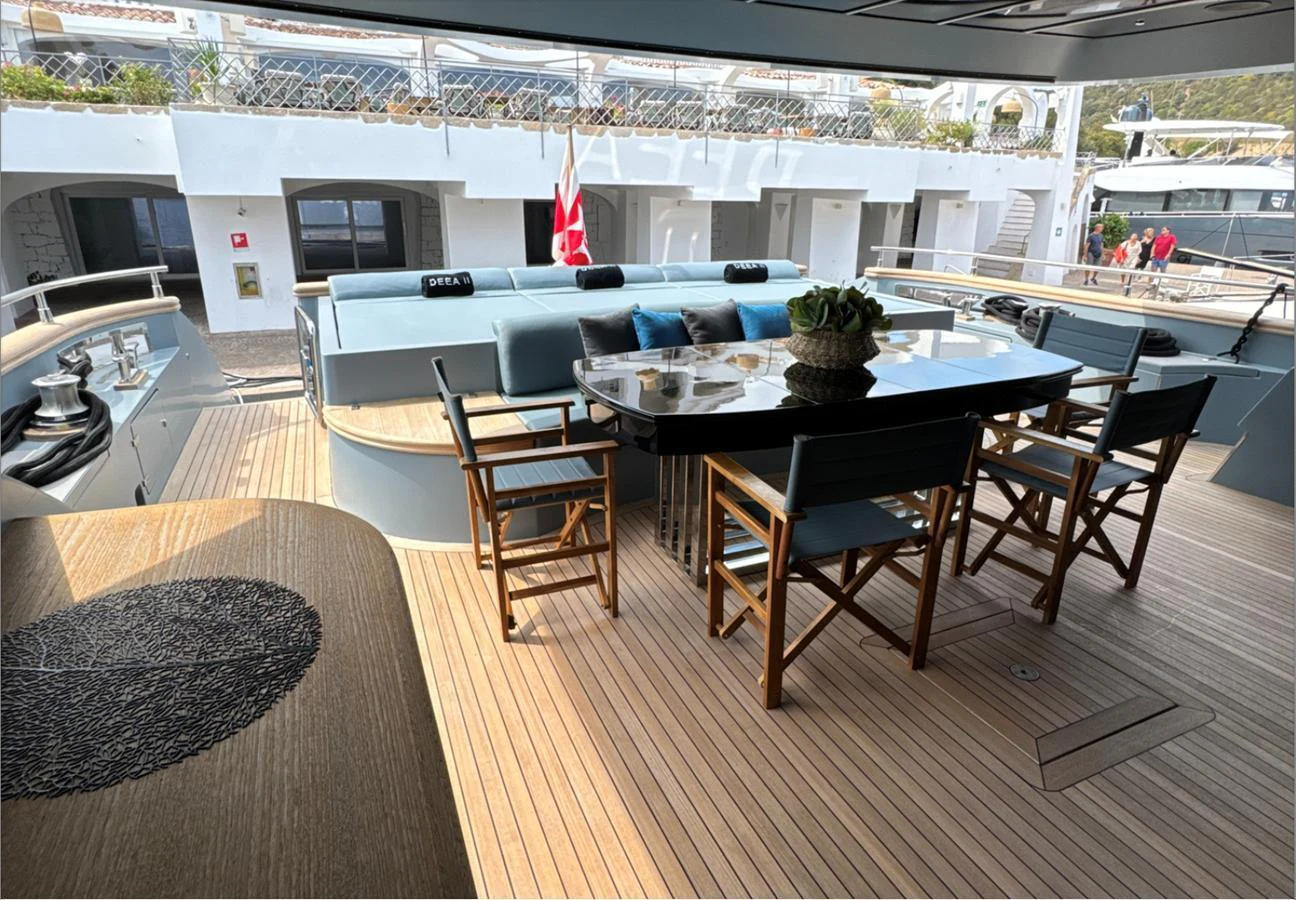 The aft deck features a stylish dining area with comfortable seating and a polished table, perfect for al fresco meals. aboard DEEA II Yacht for Sale