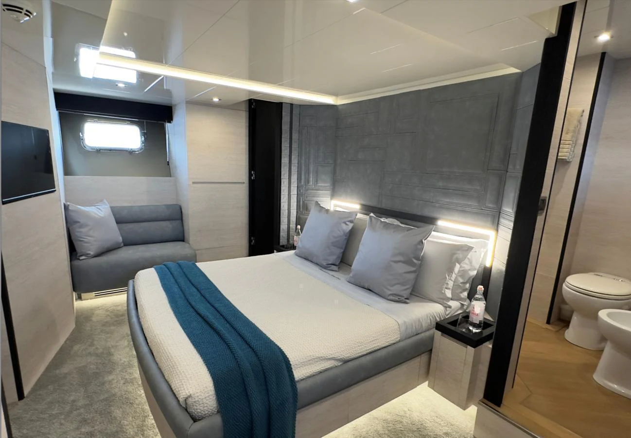 A luxurious stateroom featuring a comfortable bed with plush pillows and a cozy seating area. aboard DEEA II Yacht for Sale