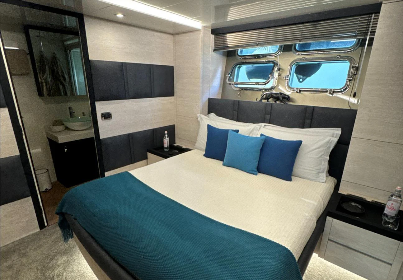 A luxurious stateroom featuring a comfortable bed with blue accents and an ensuite bathroom. aboard DEEA II Yacht for Sale