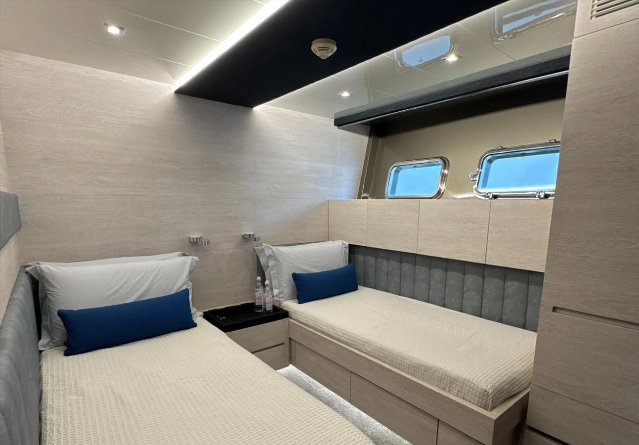 The guest stateroom features twin beds and modern decor with ample natural light. aboard DEEA II Yacht for Sale