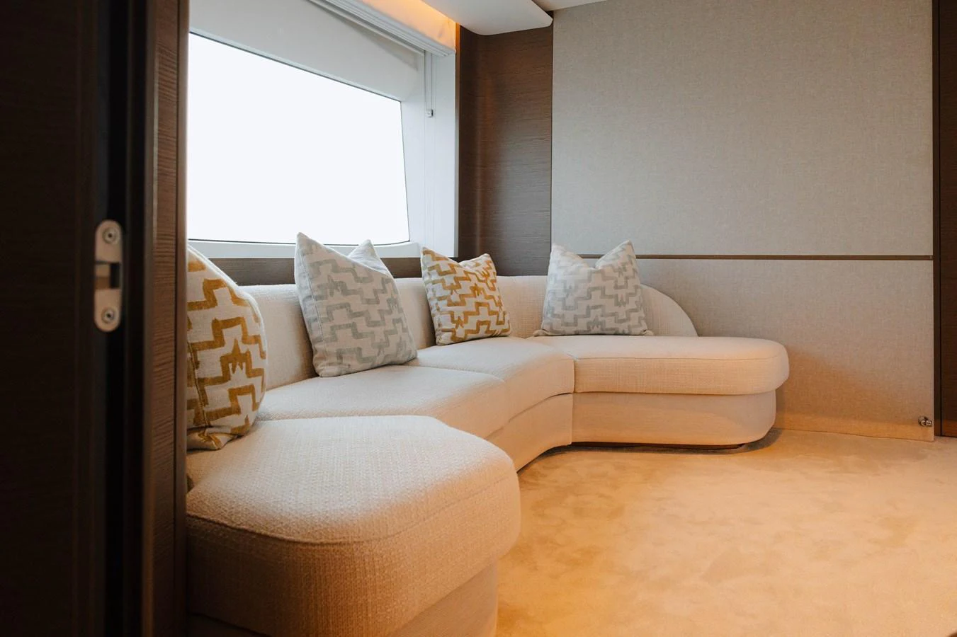 The salon features a plush, curved sofa with patterned cushions, creating a cozy and inviting atmosphere. aboard PRINCESS X95 808 Yacht for Sale