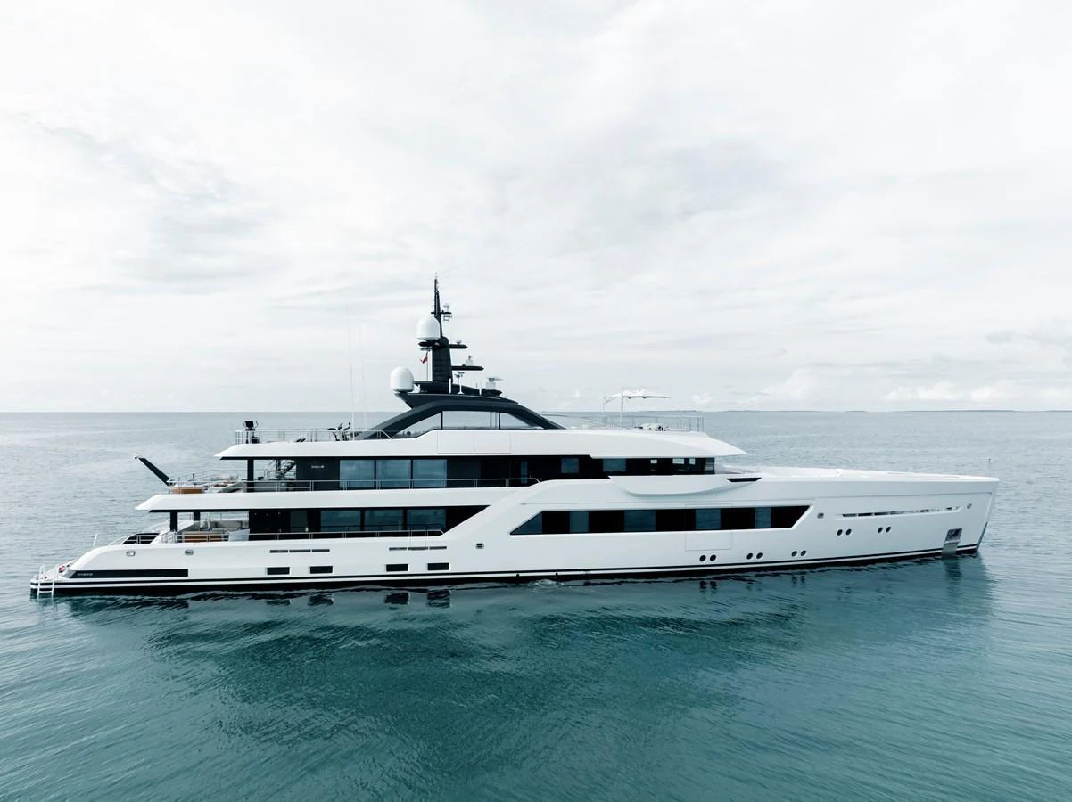 A sleek and modern yacht glides gracefully on calm waters under a cloudy sky. aboard ENTOURAGE Yacht for Sale