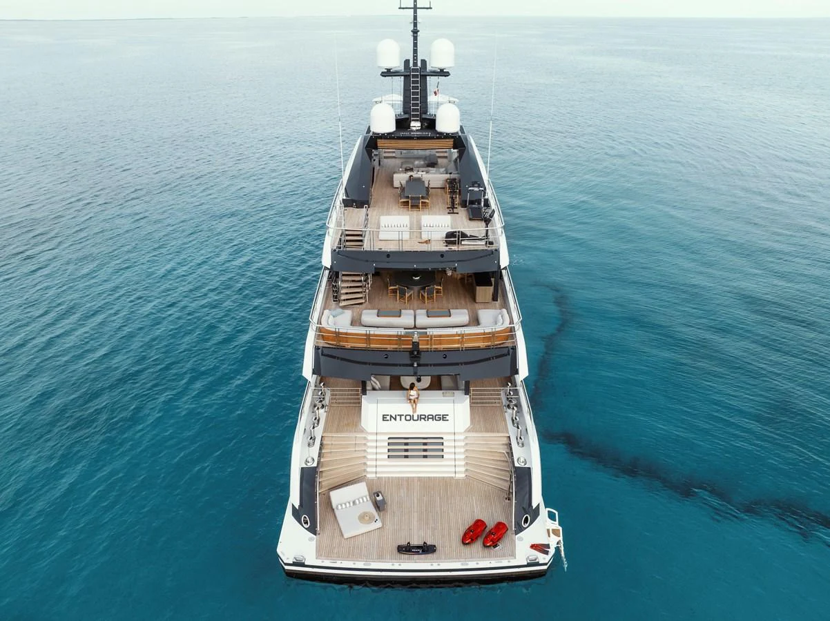 A luxurious yacht with multiple decks and ample lounging space on the aft deck, floating serenely on calm waters. aboard ENTOURAGE Yacht for Sale