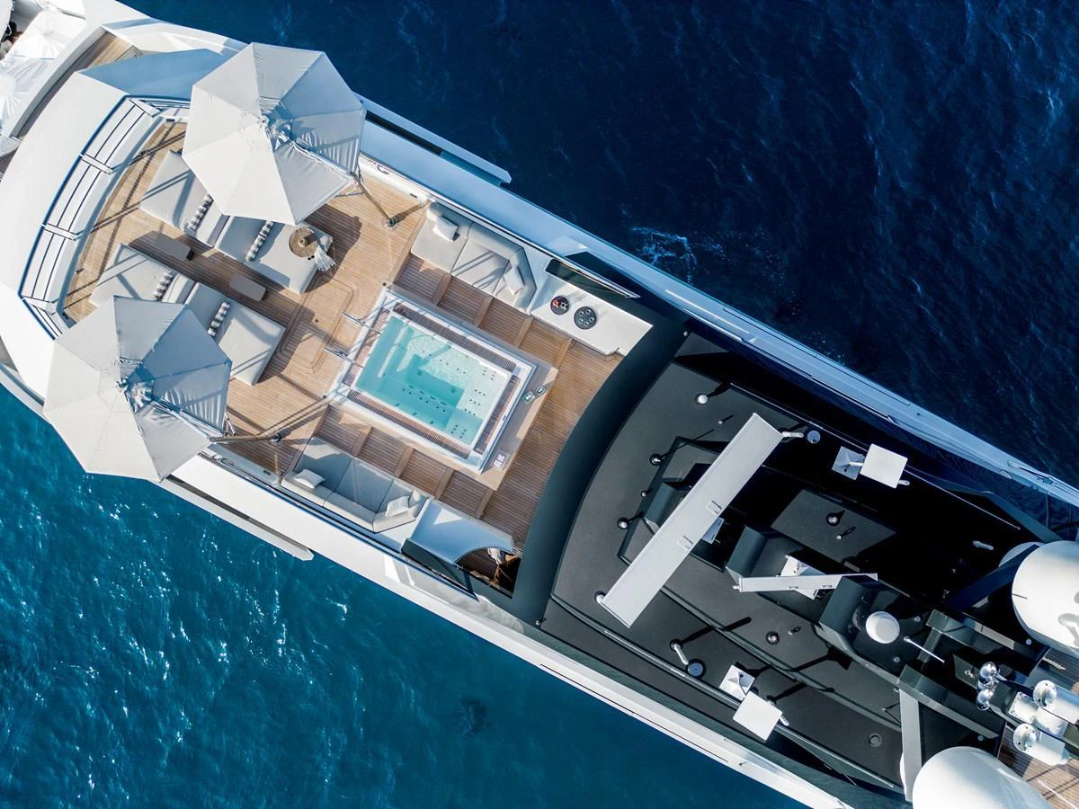 The yacht's sundeck features a luxurious pool and ample lounging space under large umbrellas. aboard ENTOURAGE Yacht for Sale