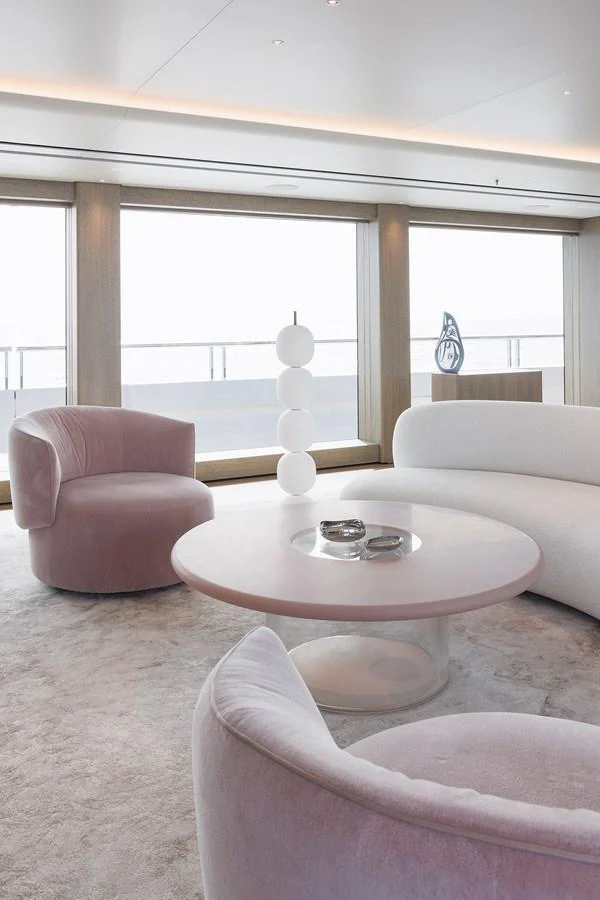 A luxurious and modern yacht interior with plush seating and large windows offering a serene ocean view. aboard ENTOURAGE Yacht for Sale