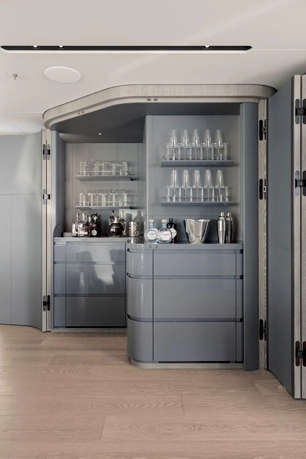 A sleek and modern bar area with a well-organized display of glassware and spirits. aboard ENTOURAGE Yacht for Sale