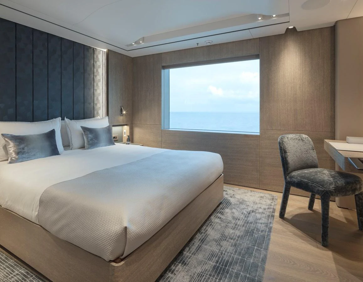 A luxurious stateroom featuring a large bed, a window with an ocean view, and elegant furnishings. aboard ENTOURAGE Yacht for Sale