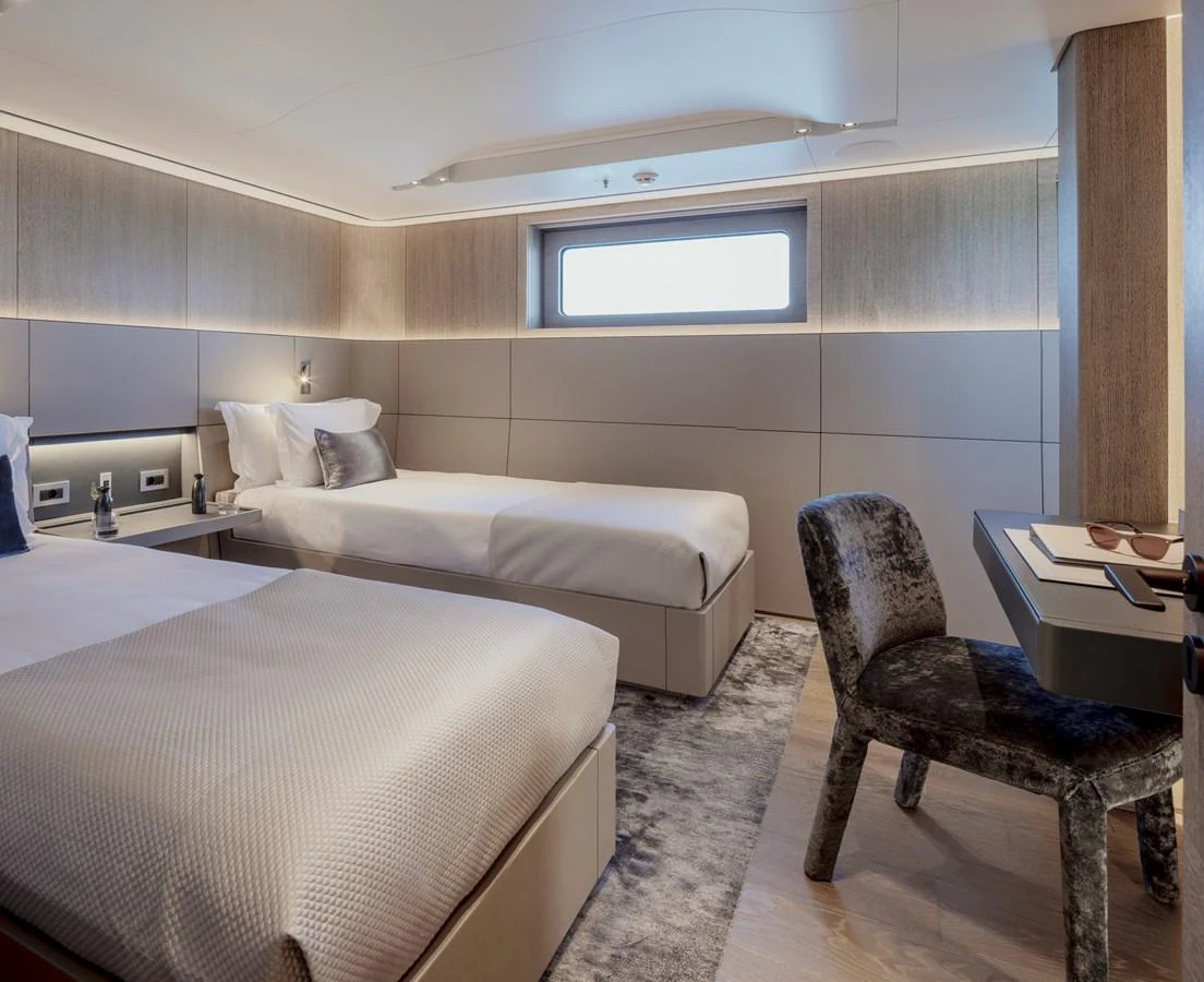 The guest stateroom offers a serene and comfortable space with twin beds and modern decor. aboard ENTOURAGE Yacht for Sale