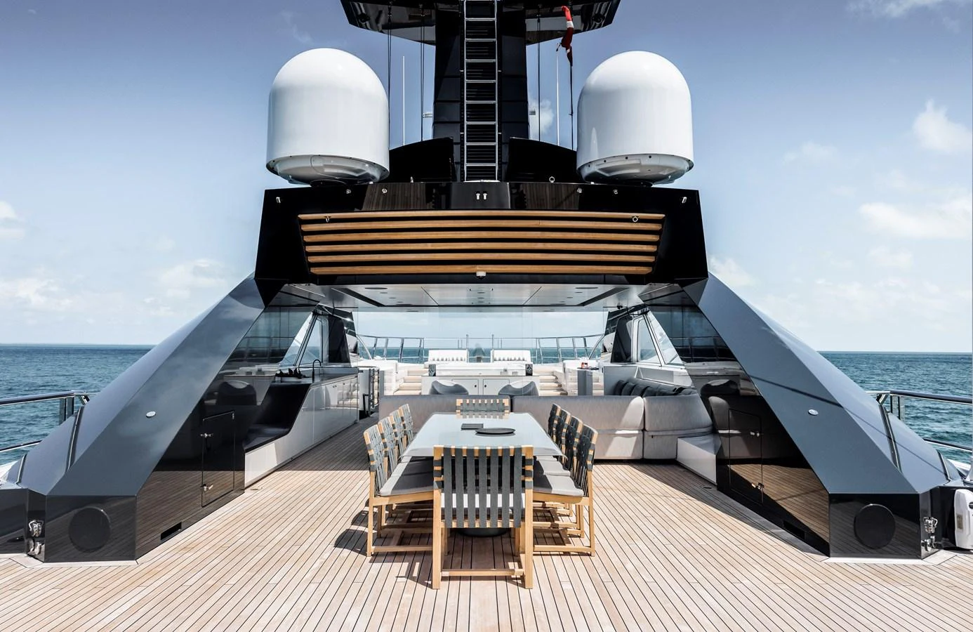 The aft deck features a spacious dining area with modern seating and panoramic ocean views. aboard ENTOURAGE Yacht for Sale