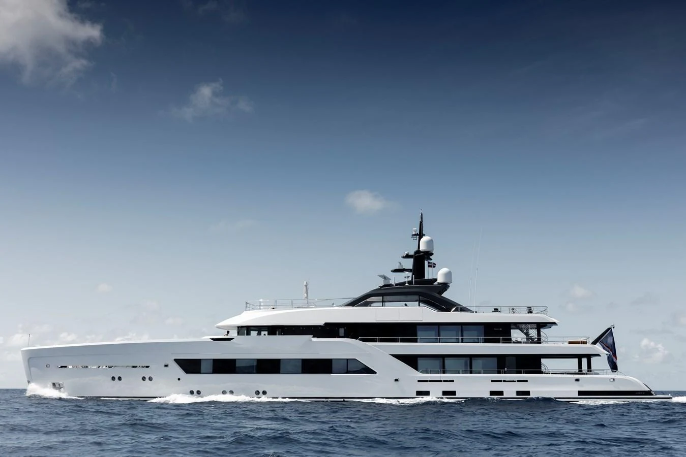 A sleek and modern yacht cruising on the open sea under a clear sky. aboard ENTOURAGE Yacht for Sale