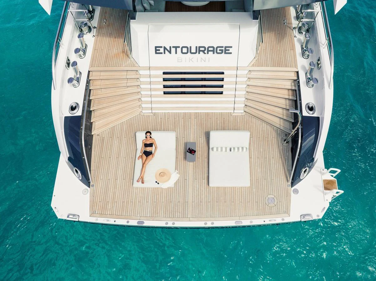 The aft deck features a spacious lounging area with a sunbathing woman and luxurious amenities. aboard ENTOURAGE Yacht for Sale