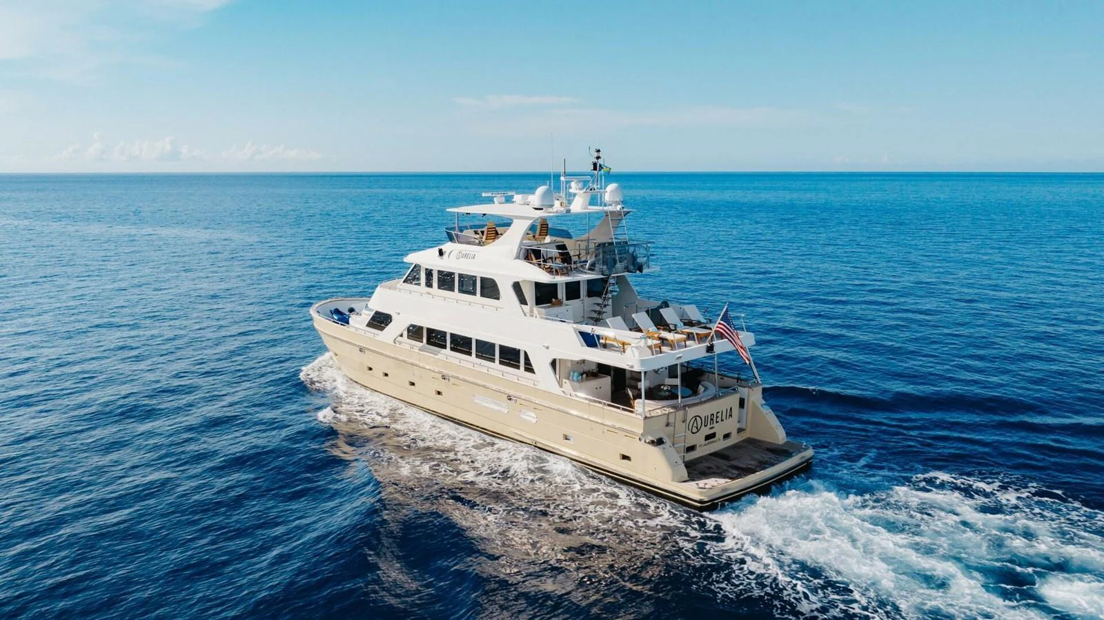 A luxurious yacht cruises through the open sea under a clear blue sky. aboard AURELIA Yacht for Sale