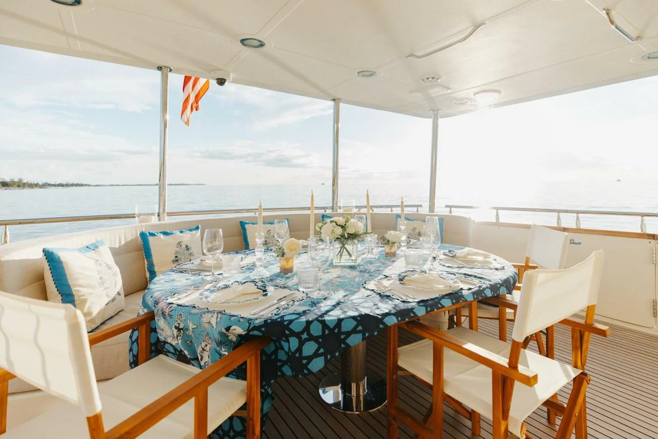 The aft deck features an elegant dining area with a beautifully set table, perfect for enjoying meals with a view of the sea. aboard AURELIA Yacht for Sale