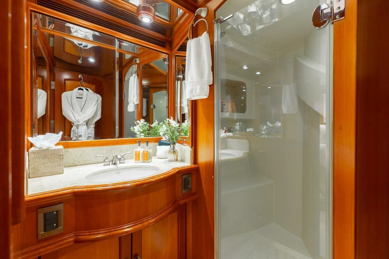 The yacht's bathroom features elegant wood cabinetry and a glass-enclosed shower. aboard AURELIA Yacht for Sale