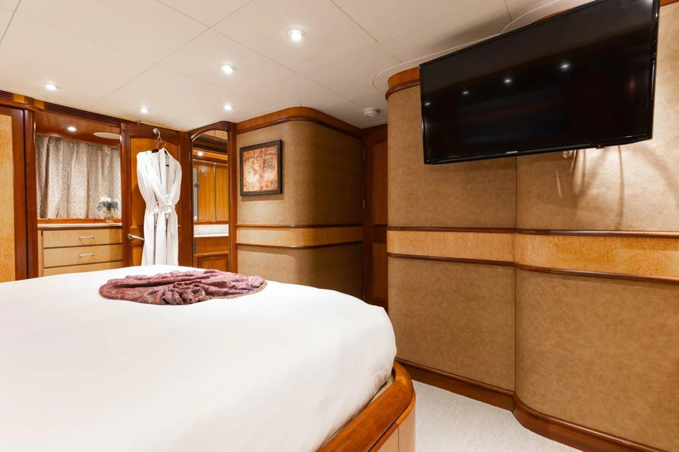 The stateroom features elegant wood paneling, a large bed, and a mounted flat-screen TV for a luxurious stay. aboard AURELIA Yacht for Sale