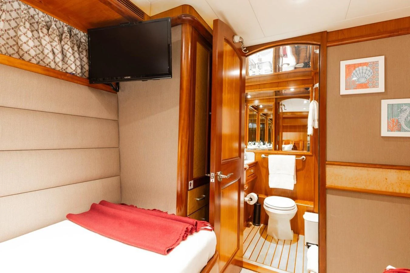 A cozy guest stateroom featuring a comfortable bed, television, and en-suite bathroom. aboard AURELIA Yacht for Sale