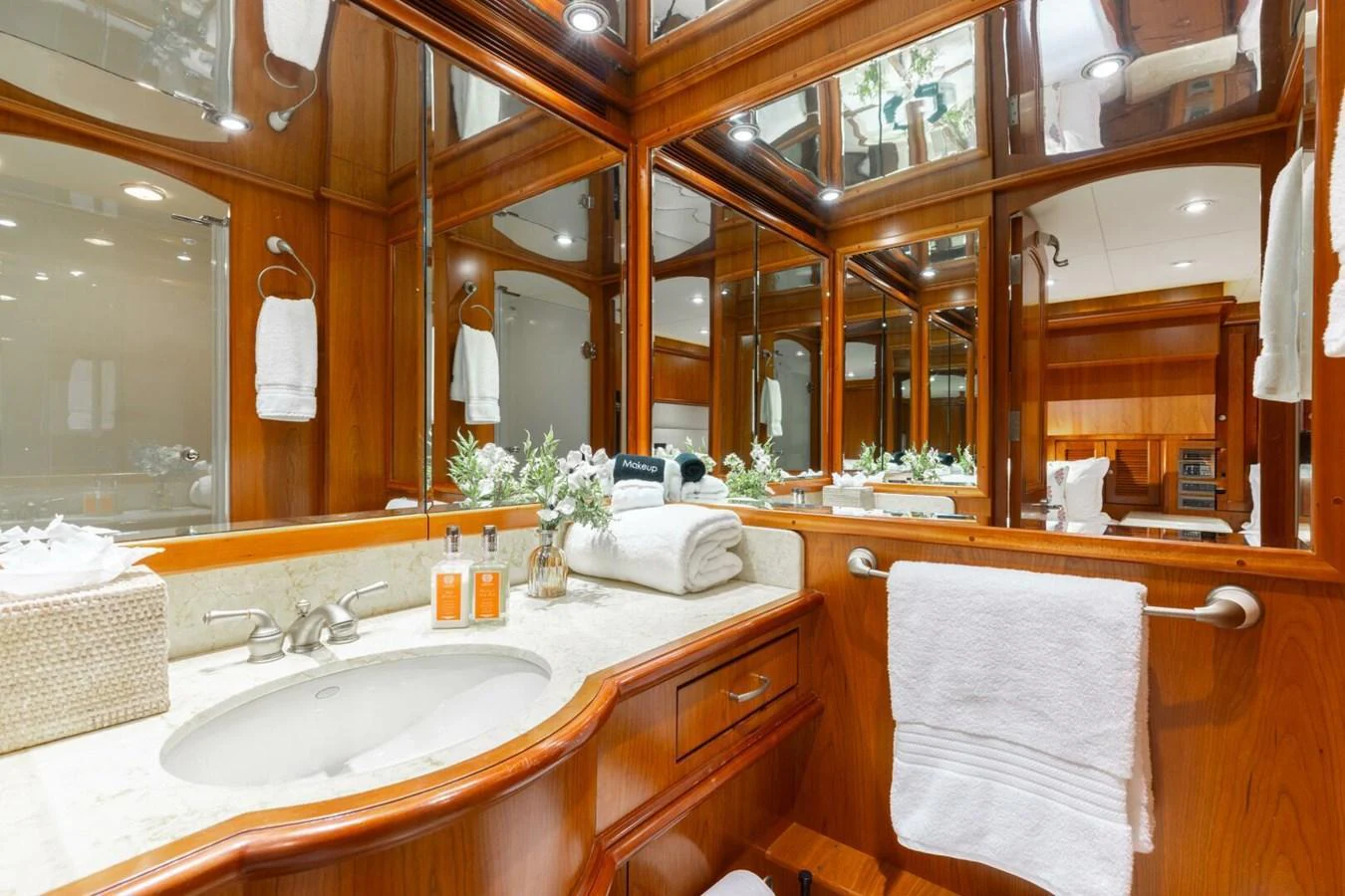 The yacht's bathroom features elegant wood paneling, a marble countertop, and ample mirrors for a luxurious feel. aboard AURELIA Yacht for Sale