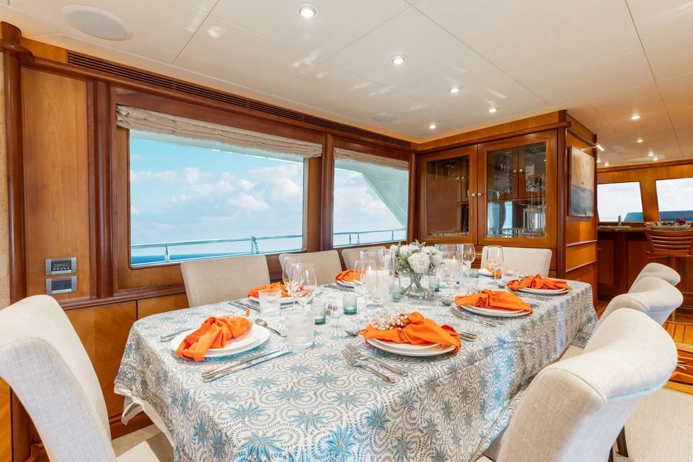 The yacht's dining area features an elegantly set table with a view of the ocean through large windows. aboard AURELIA Yacht for Sale