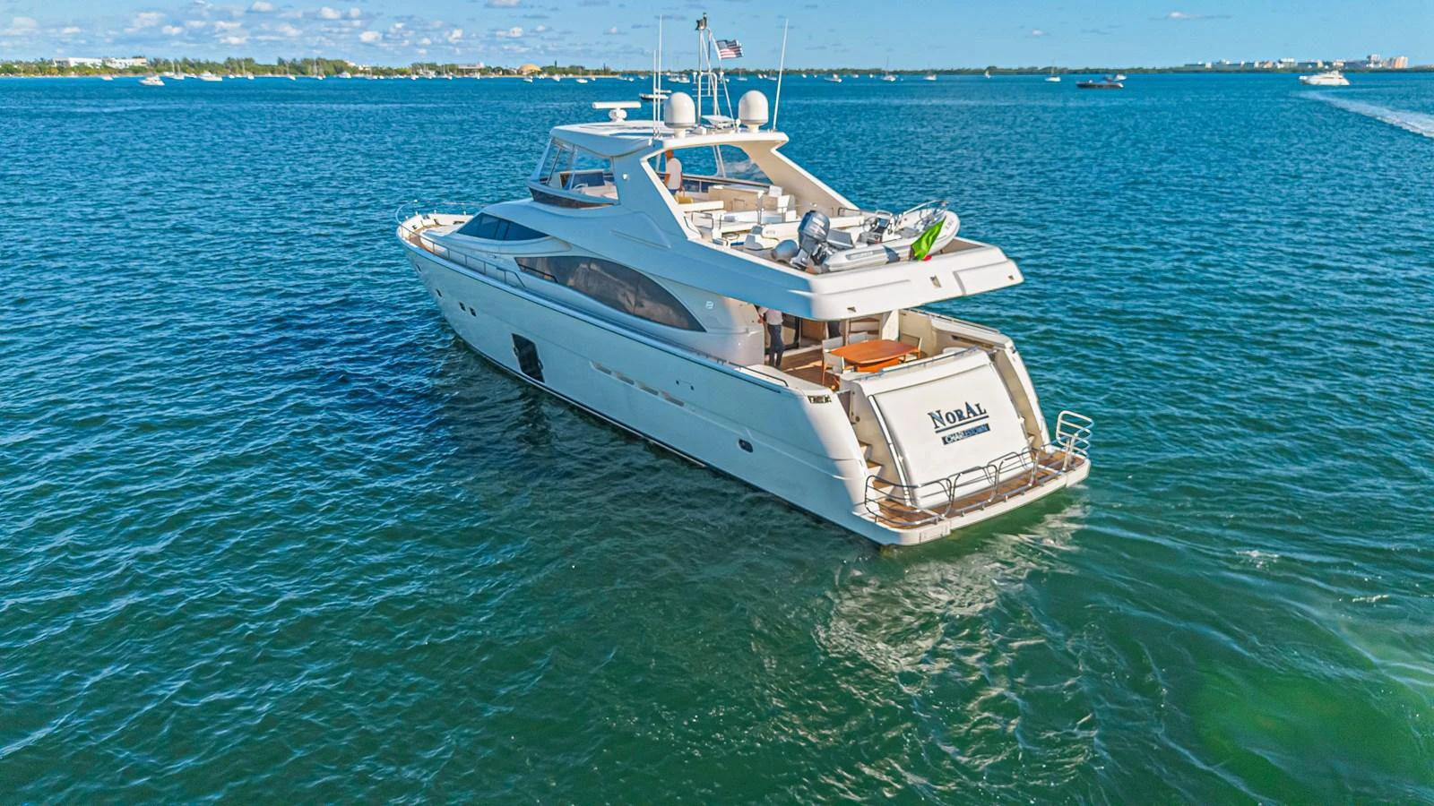 A sleek yacht glides gracefully on calm blue waters, showcasing its elegant design and spacious deck. aboard NORAL Yacht for Sale