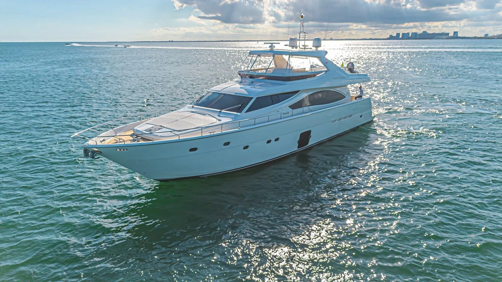 A sleek and modern yacht cruising on calm waters with a cityscape in the background. aboard NORAL Yacht for Sale