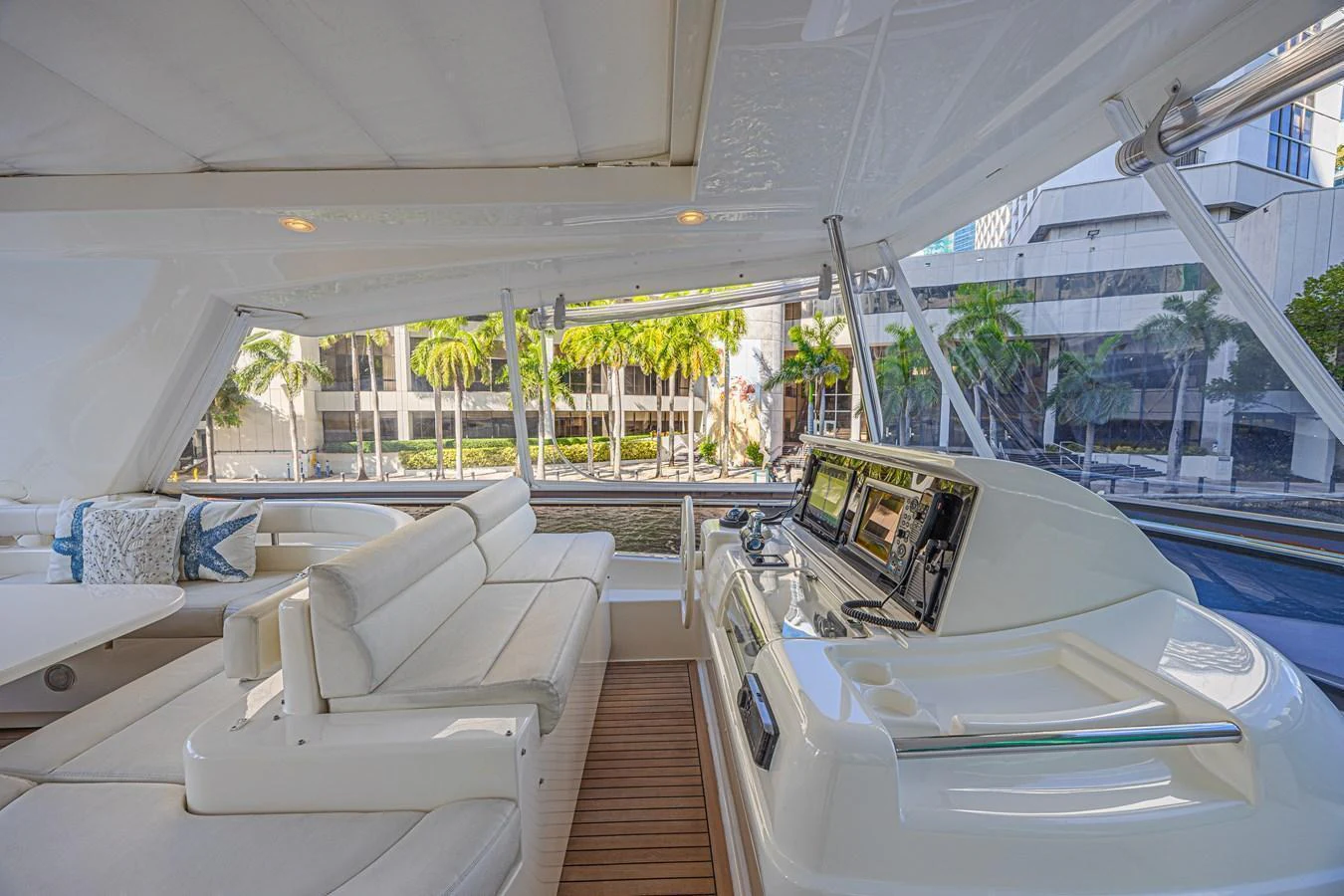 The yacht's helm area features a sleek control panel and comfortable seating with a view of the water and surrounding buildings. aboard NORAL Yacht for Sale