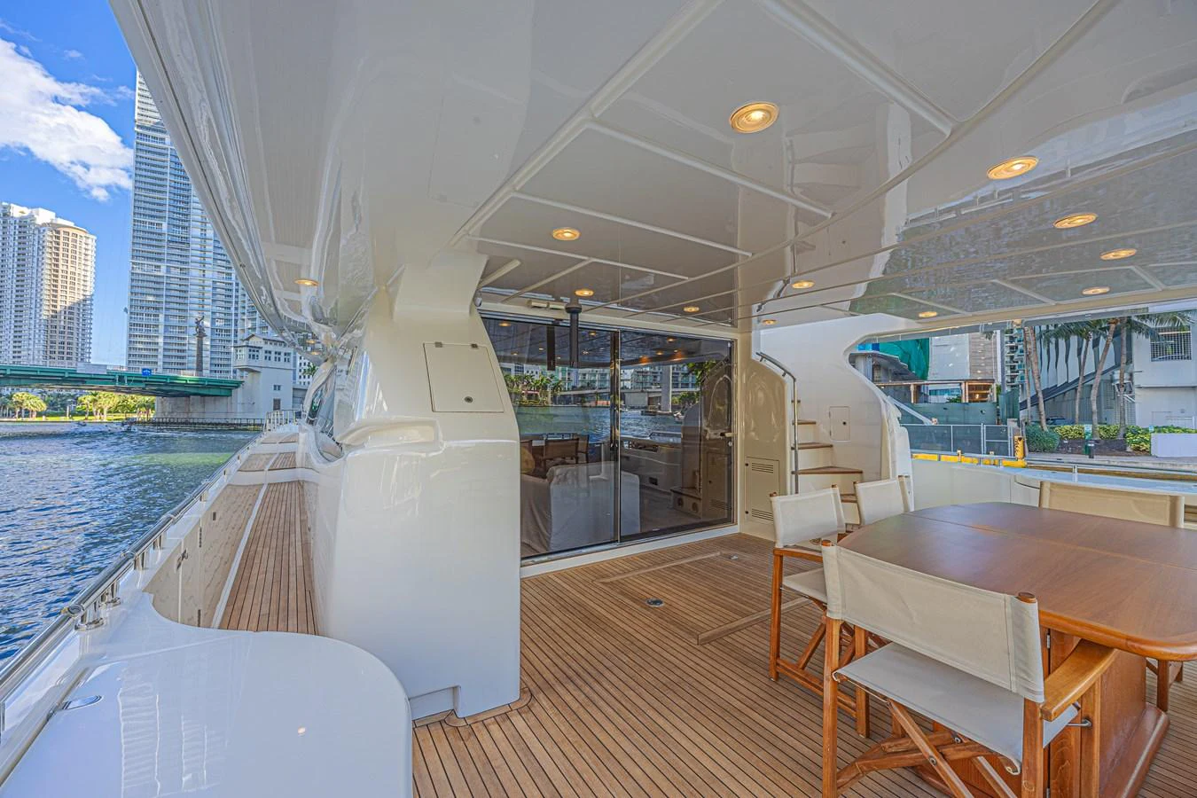 The yacht's aft deck features a spacious seating area with a wooden table and chairs, perfect for alfresco dining. aboard NORAL Yacht for Sale