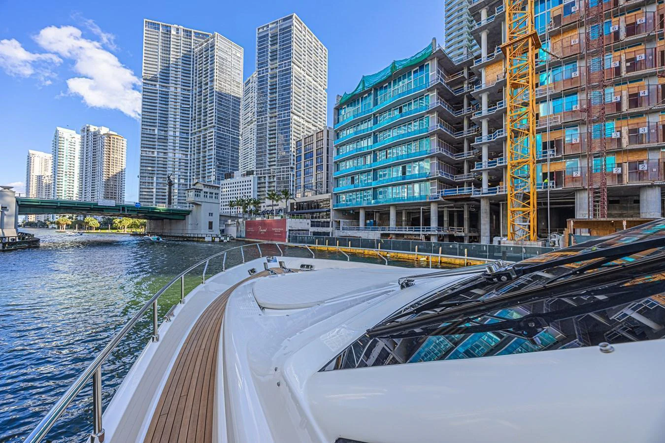 The yacht cruises along a vibrant urban waterfront, showcasing its sleek bow and modern design. aboard NORAL Yacht for Sale