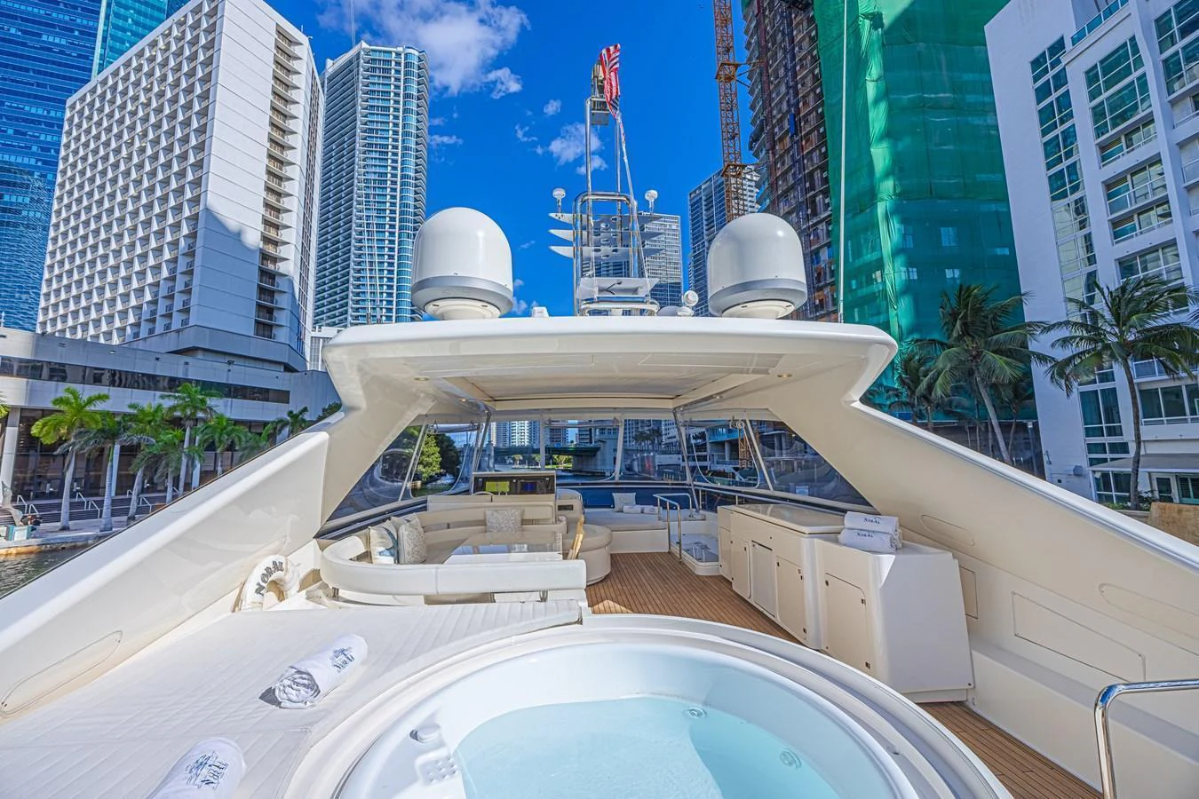 The yacht's flybridge features a spacious seating area, a jacuzzi, and a stunning cityscape backdrop. aboard NORAL Yacht for Sale
