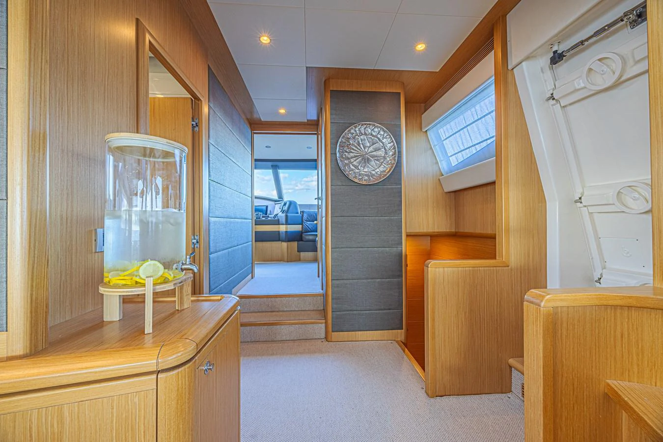 A bright and inviting interior hallway with wooden finishes and a refreshing water dispenser. aboard NORAL Yacht for Sale