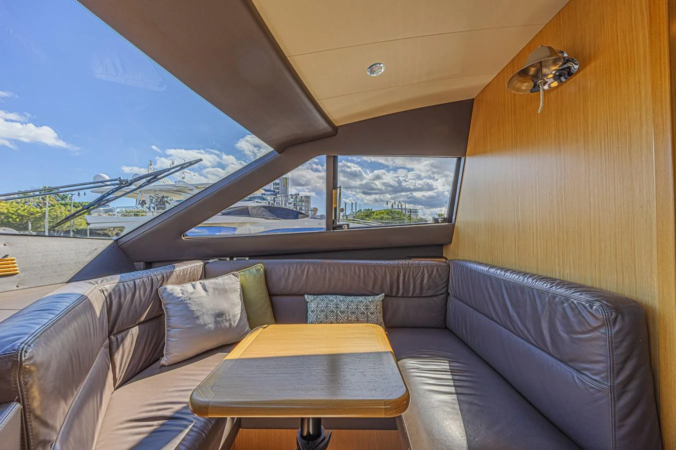 The salon features a cozy seating area with a table, surrounded by large windows offering ample natural light. aboard NORAL Yacht for Sale