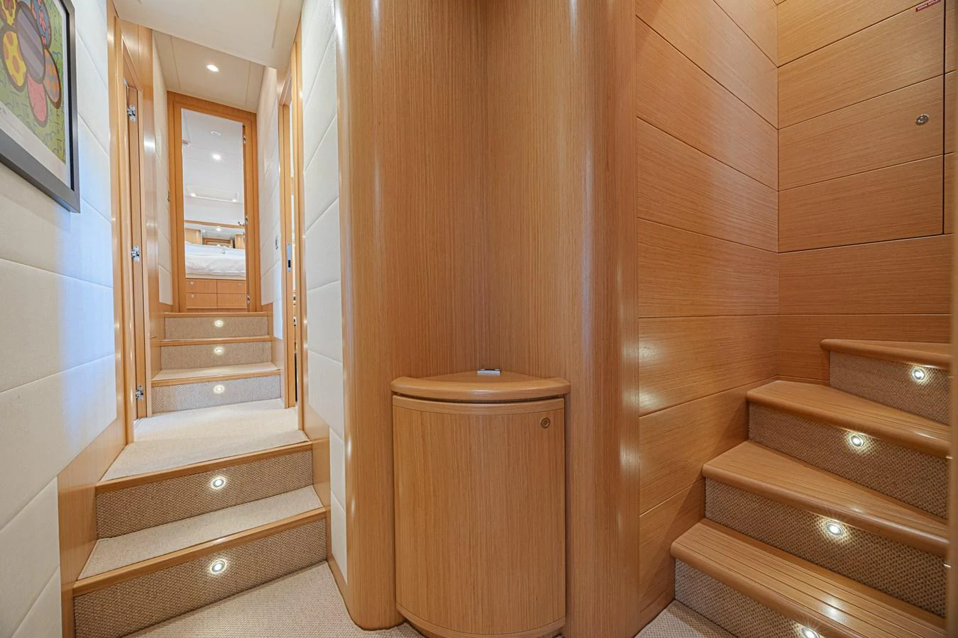 The yacht's interior features a well-lit hallway with wooden paneling and carpeted stairs leading to different sections. aboard NORAL Yacht for Sale