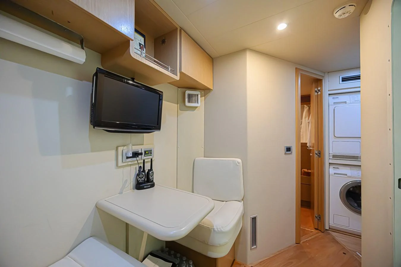 The crew quarters feature practical amenities including a small desk, seating area, and laundry facilities. aboard NORAL Yacht for Sale