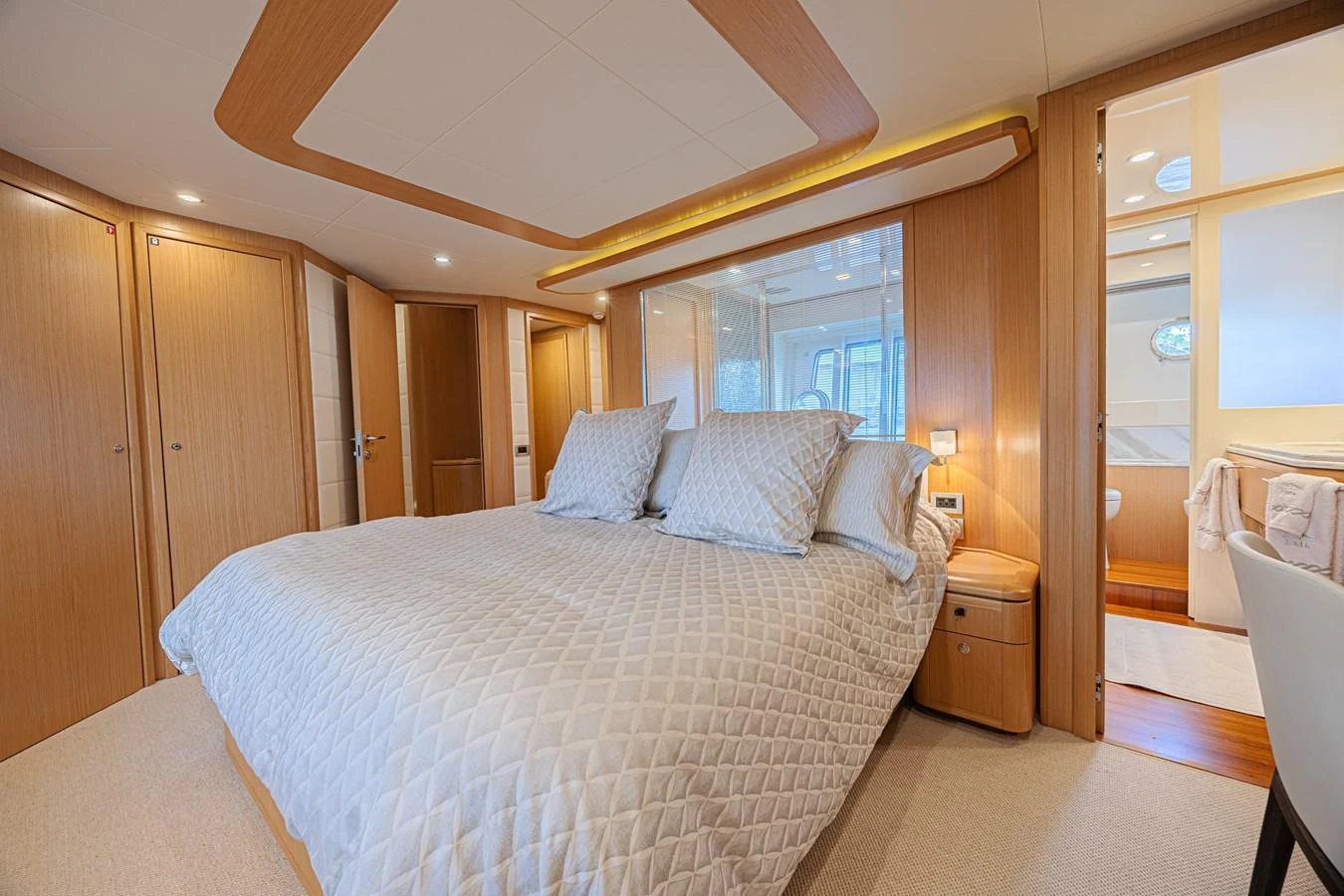 The master stateroom features a luxurious bed with elegant bedding and warm wood finishes. aboard NORAL Yacht for Sale