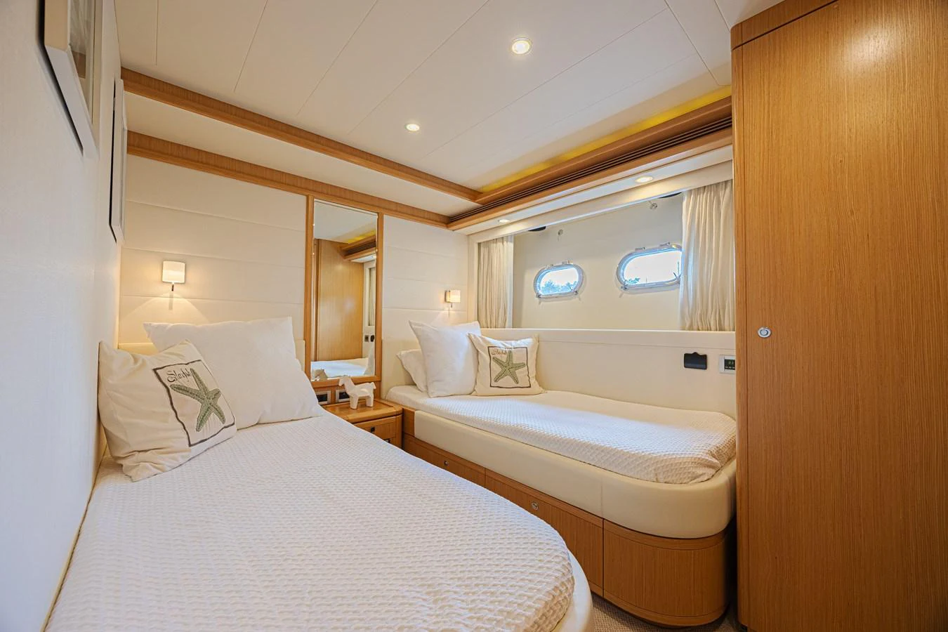 The guest stateroom features twin beds, warm wood finishes, and soft lighting for a cozy retreat. aboard NORAL Yacht for Sale