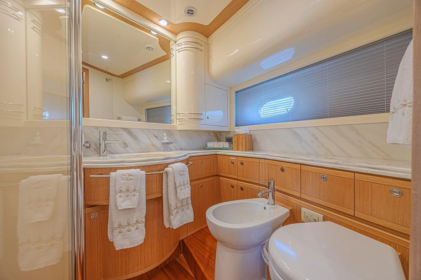 The yacht's bathroom features elegant wood cabinetry and modern fixtures, creating a luxurious and comfortable space. aboard NORAL Yacht for Sale