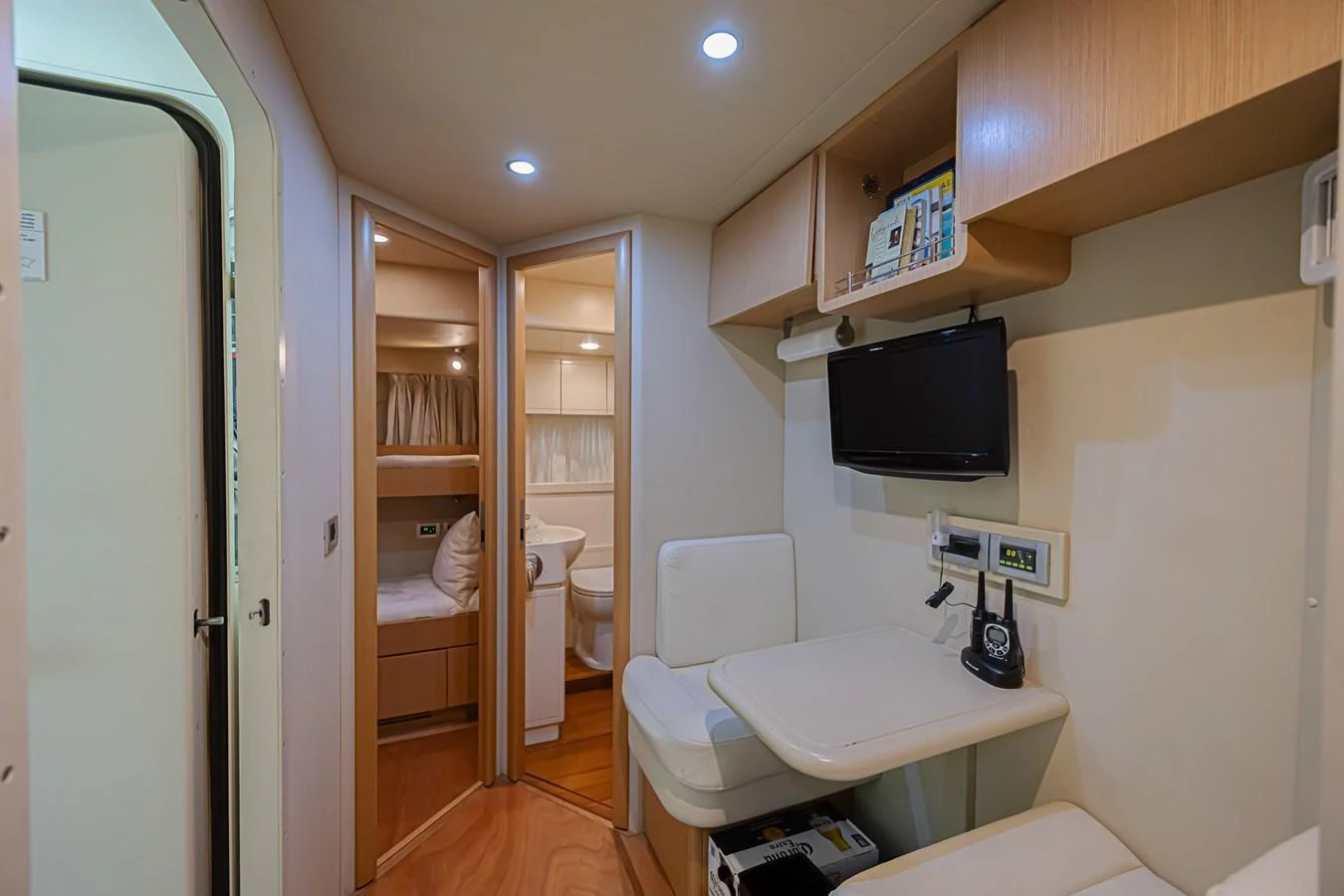 The cozy cabin features a small dining area, a television, and access to a sleeping area and bathroom. aboard NORAL Yacht for Sale