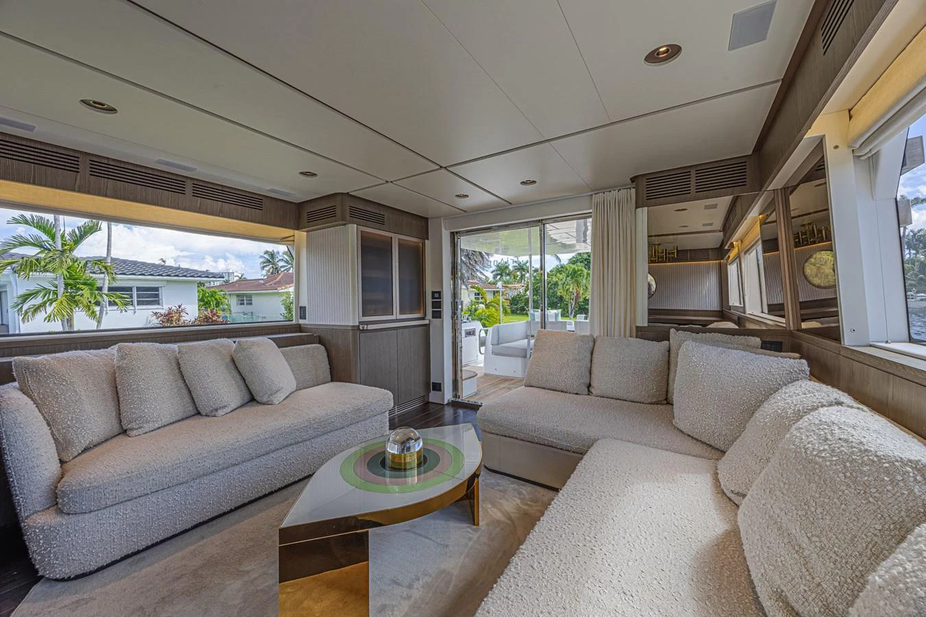The salon features plush seating with large windows offering a view of the outdoors. aboard XAX66M61L122 Yacht for Sale