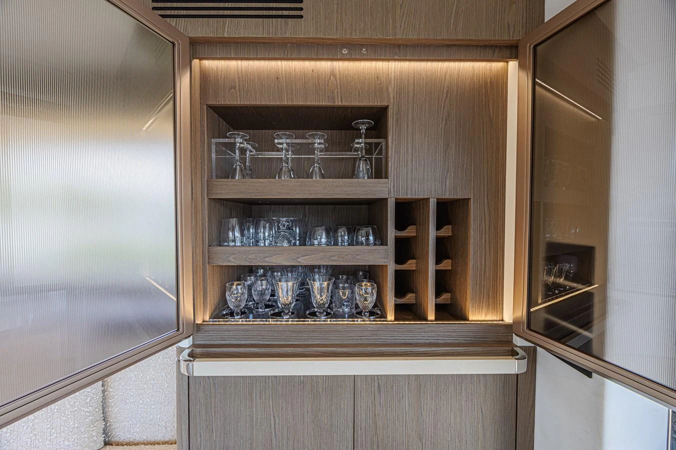 The yacht's galley features a well-organized glassware and wine storage area with elegant lighting. aboard XAX66M61L122 Yacht for Sale