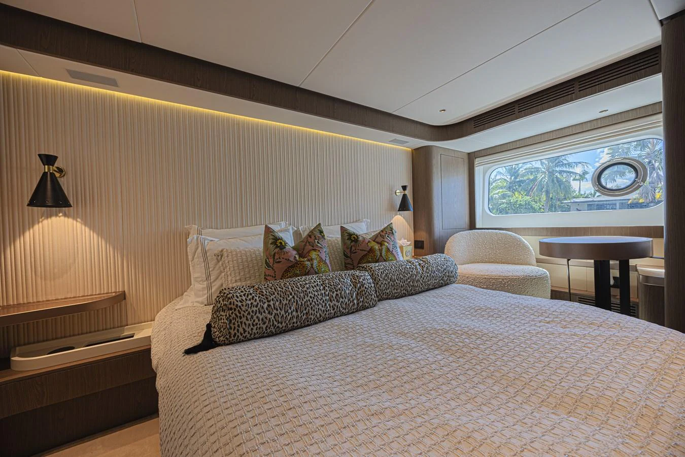 The stateroom features a luxurious bed with elegant lighting and a scenic window view. aboard XAX66M61L122 Yacht for Sale