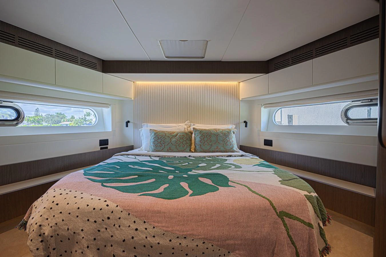 A cozy stateroom featuring a large bed with colorful bedding and ample natural light from side windows. aboard XAX66M61L122 Yacht for Sale
