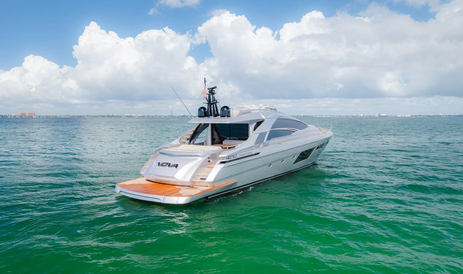 A sleek yacht cruises on calm, turquoise waters under a bright, partly cloudy sky. aboard NOVA Yacht for Sale