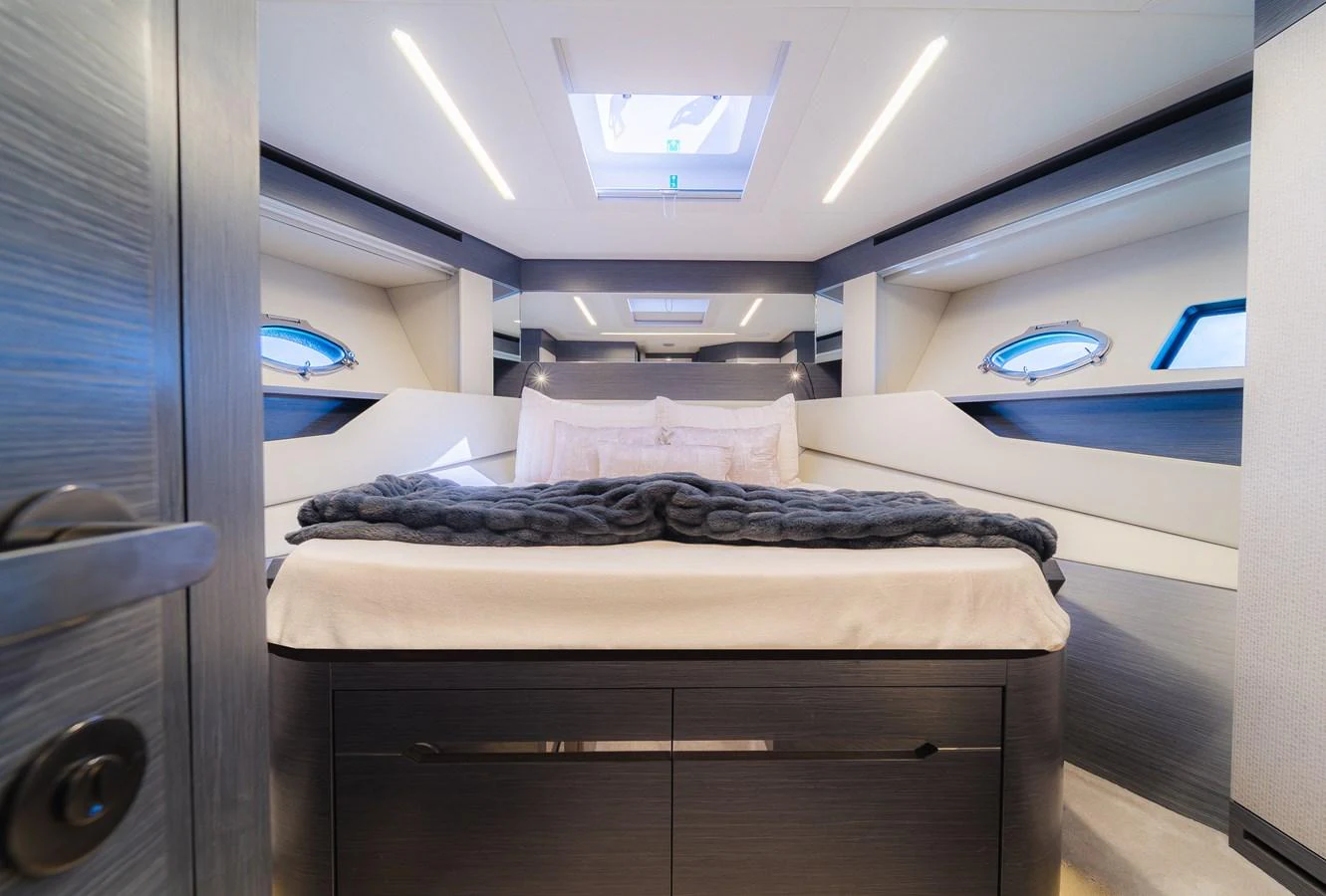 The stateroom features a luxurious bed with modern lighting and ample natural light from the skylight and portholes. aboard NOVA Yacht for Sale