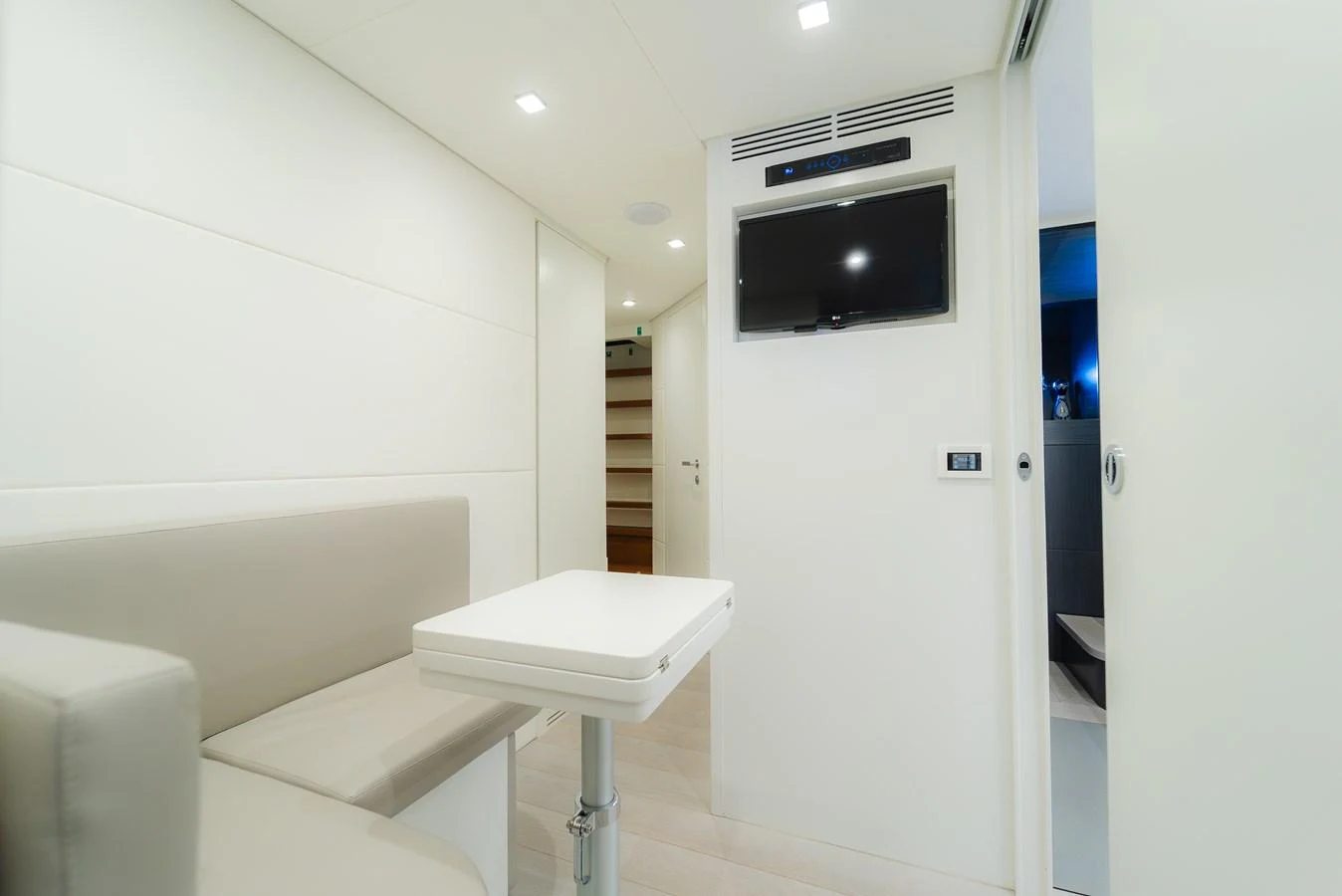 The yacht's interior features a cozy seating area with a mounted television and a foldable table. aboard NOVA Yacht for Sale