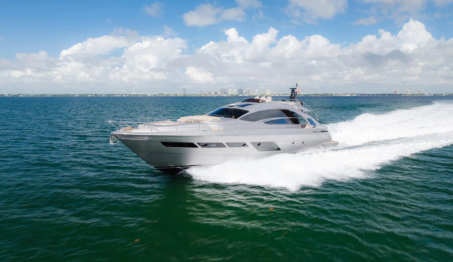 A sleek, modern yacht cruises swiftly across the open water under a bright, clear sky. aboard NOVA Yacht for Sale