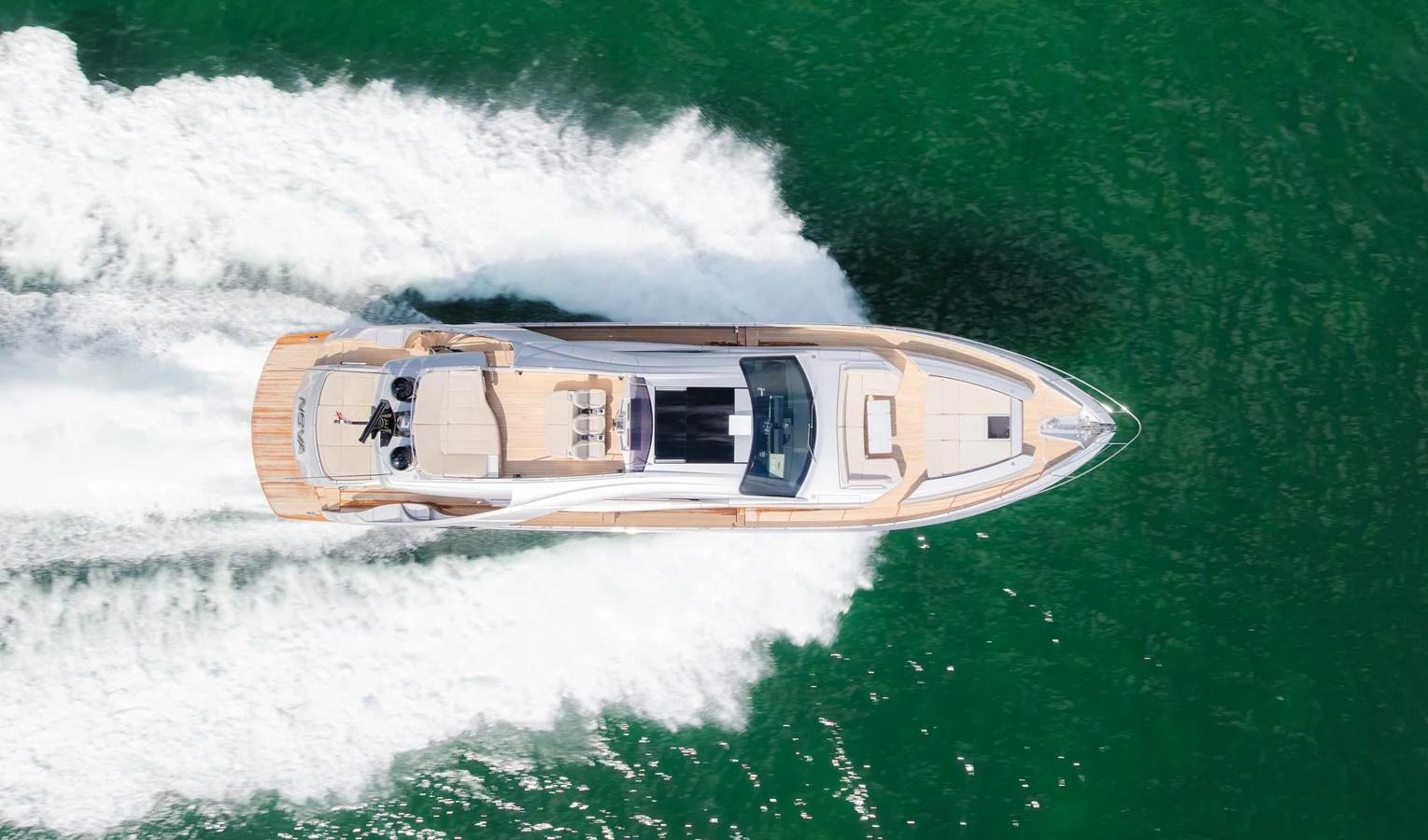A sleek yacht cruises swiftly through emerald green waters, leaving a trail of white wake behind. aboard NOVA Yacht for Sale