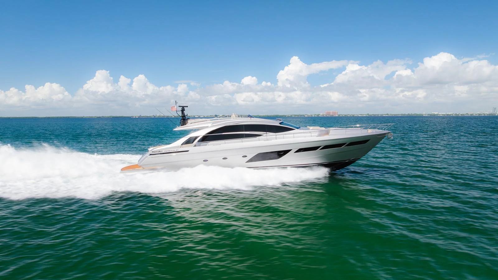 A sleek yacht glides swiftly across the water under a clear blue sky. aboard NOVA Yacht for Sale